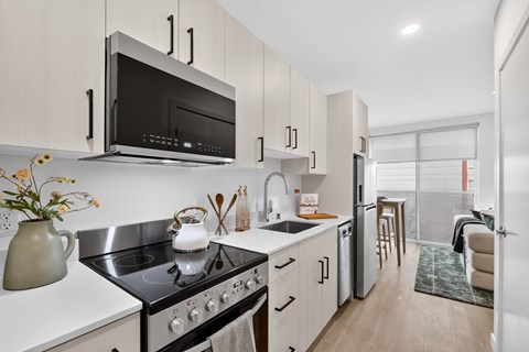 A modern kitchen with a black stove top oven and white cabinets.