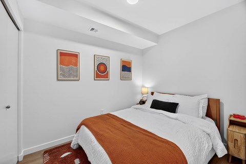 A bedroom with a bed, pillows, and pictures on the wall.