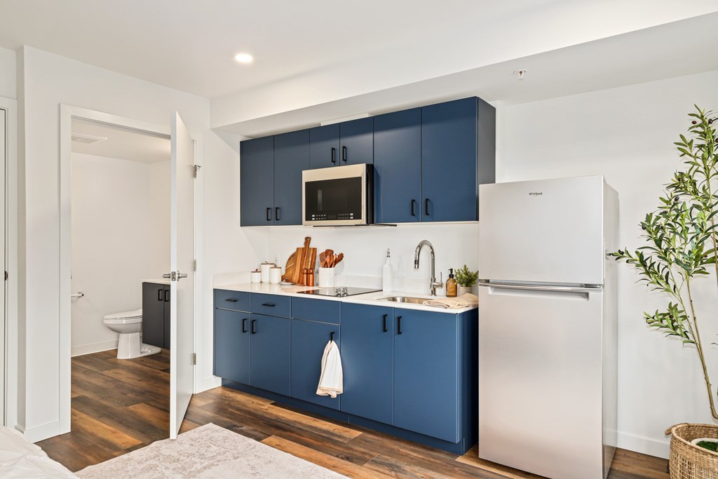 A kitchen with blue cabinets and a white refrigerator.