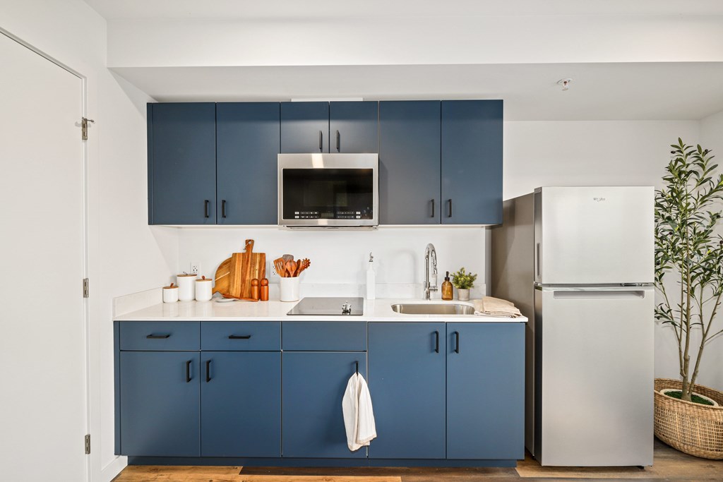 A kitchen with blue cabinets and a white refrigerator.