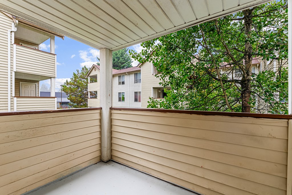 a balcony with a wood privacy fence and a view of trees