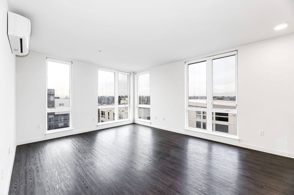 an empty living room with wood floors and large windows