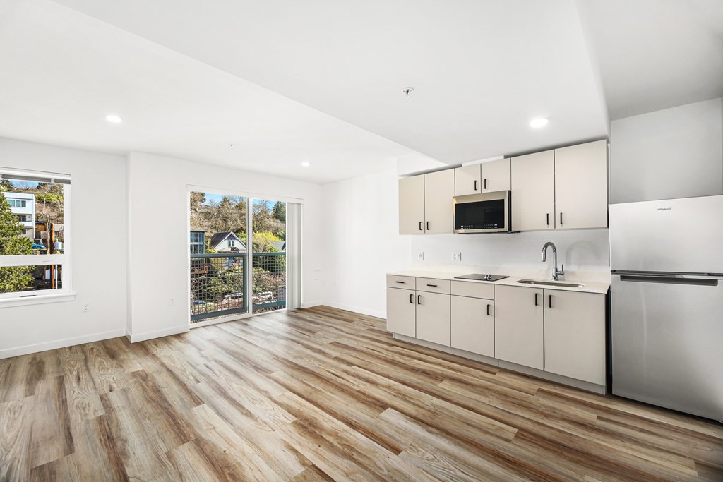 A kitchen with white cabinets and a wooden floor.