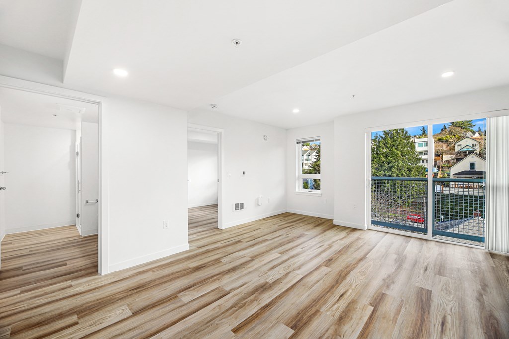 A spacious room with wooden flooring and white walls.