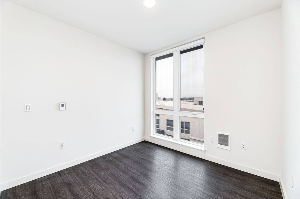 an empty living room with a large window and wood flooring