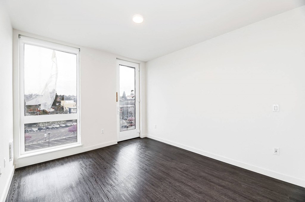 an empty living room with wood floors and a window