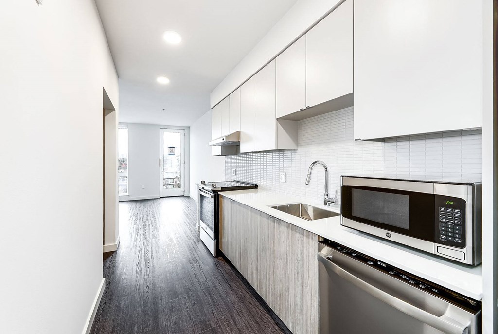 a white kitchen with a microwave and a sink