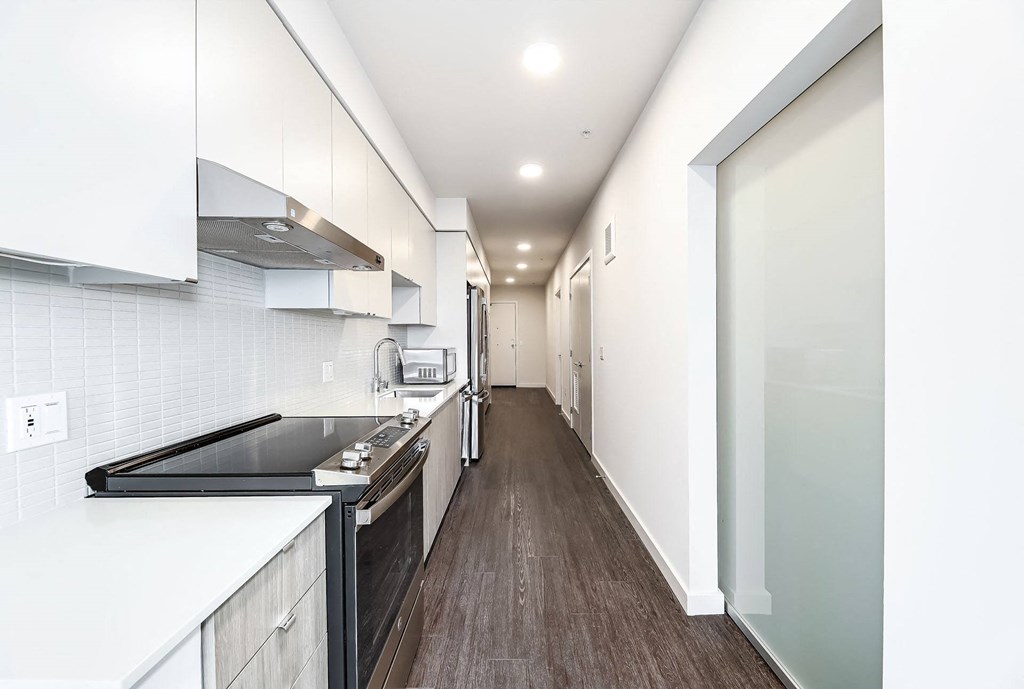 a long kitchen with white cabinets and black counter tops