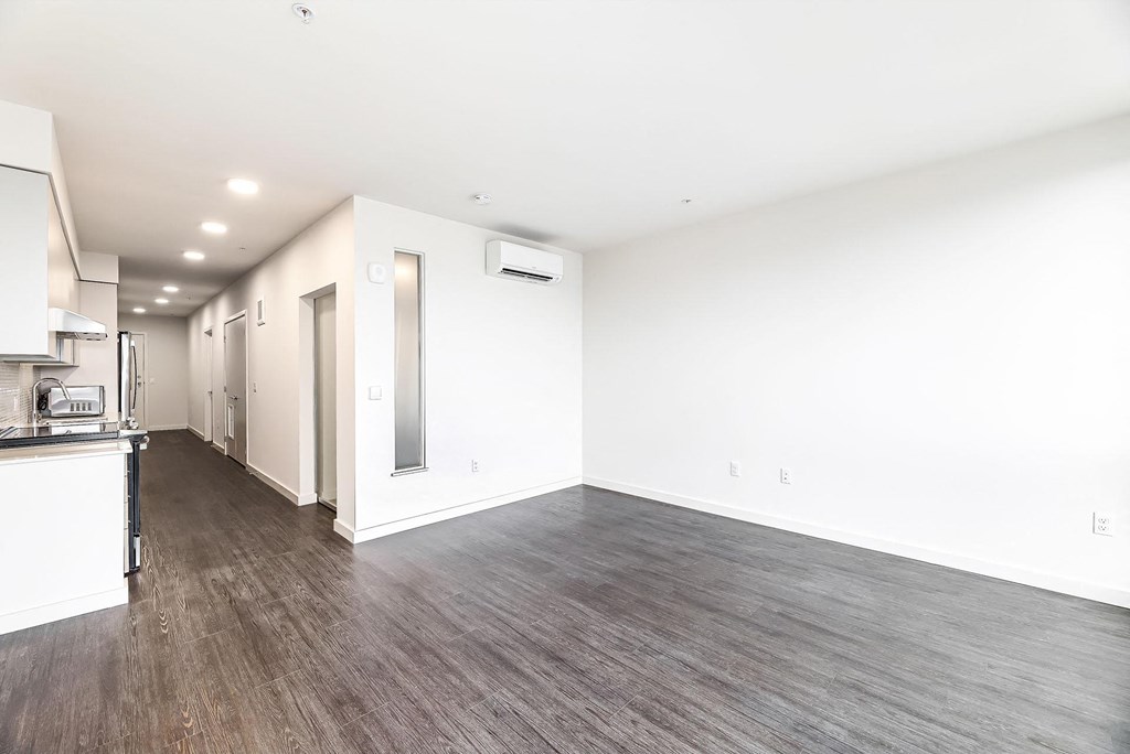 a living room and kitchen with white walls and wood floors