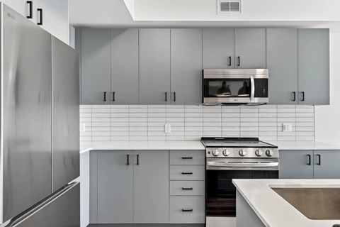 A modern kitchen with a stainless steel refrigerator and a microwave above the stove.