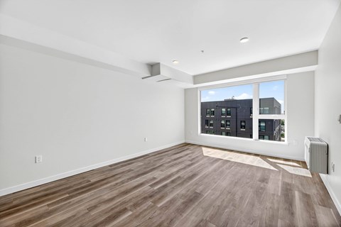 A room with wooden flooring and a large window overlooking a cityscape.