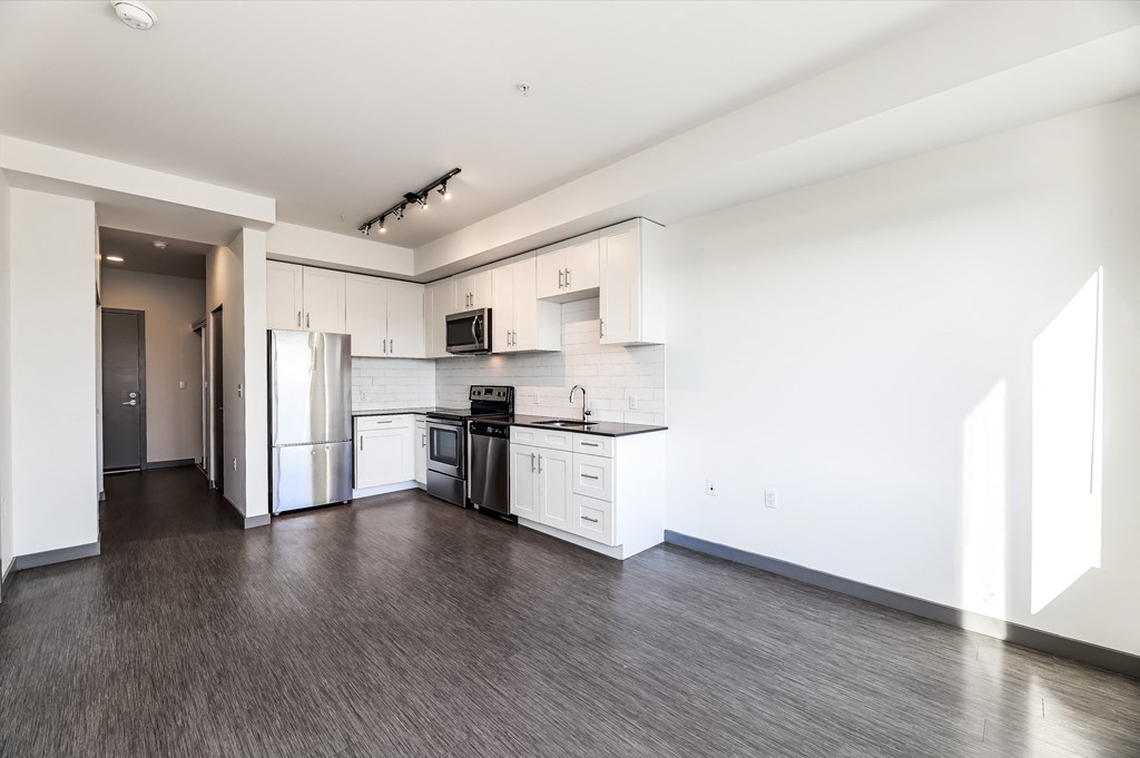 an empty kitchen with white cabinets and stainless steel appliances