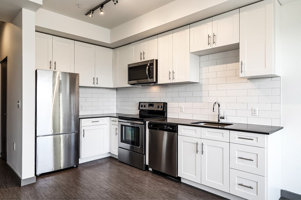 a white kitchen with stainless steel appliances and white cabinets