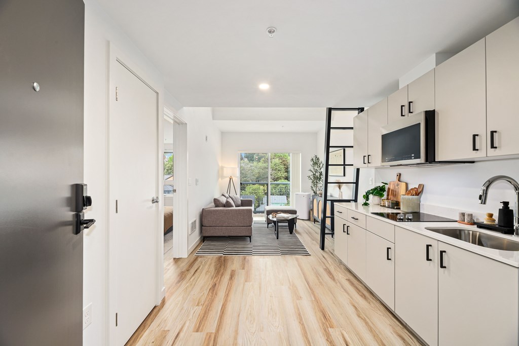 A modern kitchen with white cabinets and a wooden floor.