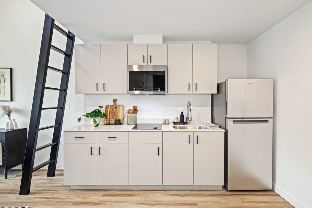 A white kitchen with a black ladder.