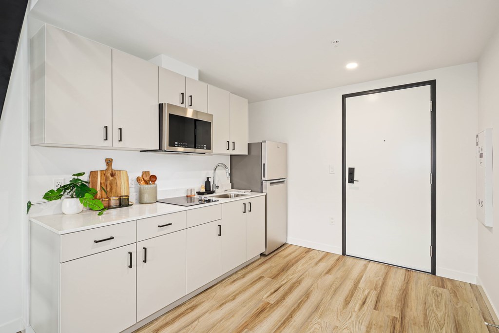 A kitchen with white cabinets and a black door.