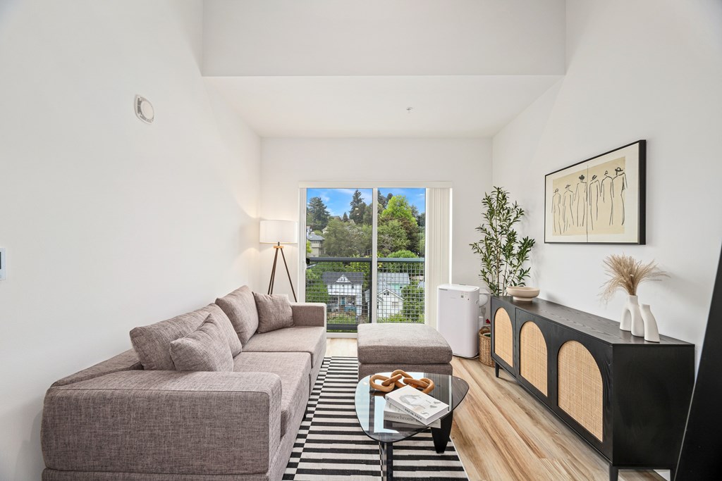 A living room with a grey couch and a black and white striped rug.