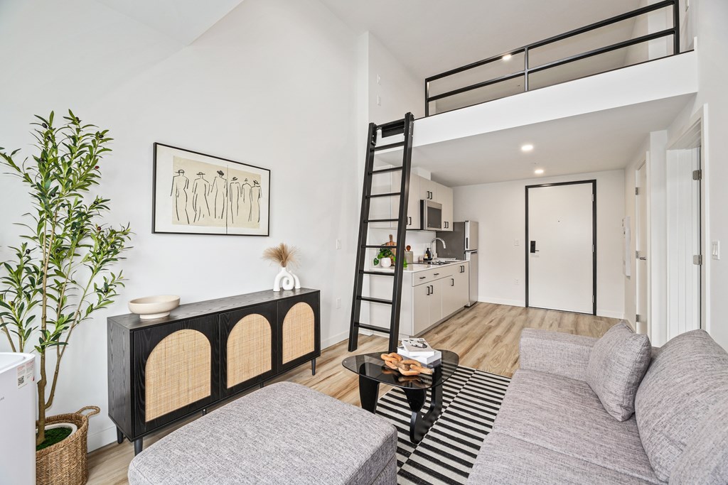 A living room with a grey couch and a black and white striped rug.