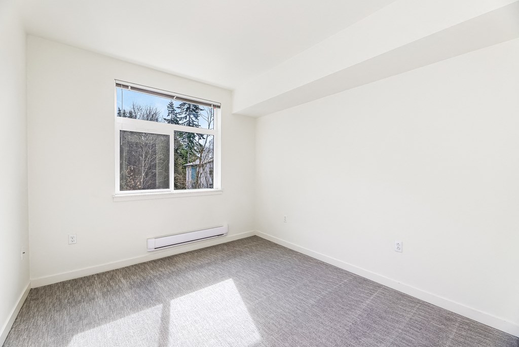 a bedroom with a large window and a carpeted floor