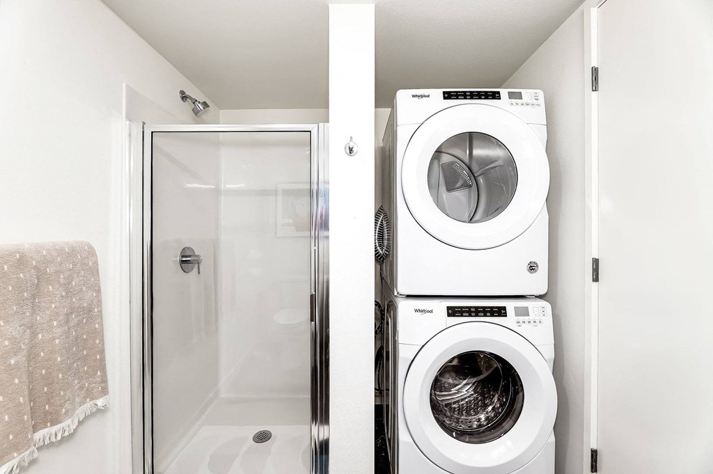 a washer and dryer in a bathroom next to a shower