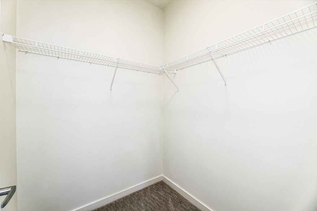 a small room with white walls and a white wire shelf