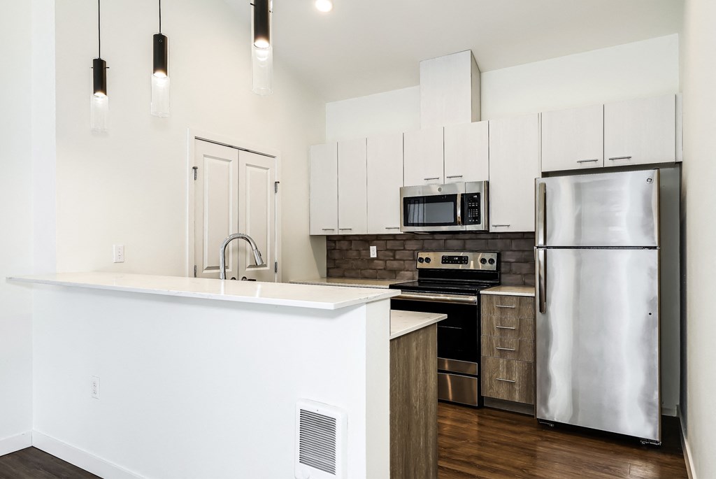a white kitchen with stainless steel appliances and a white counter top