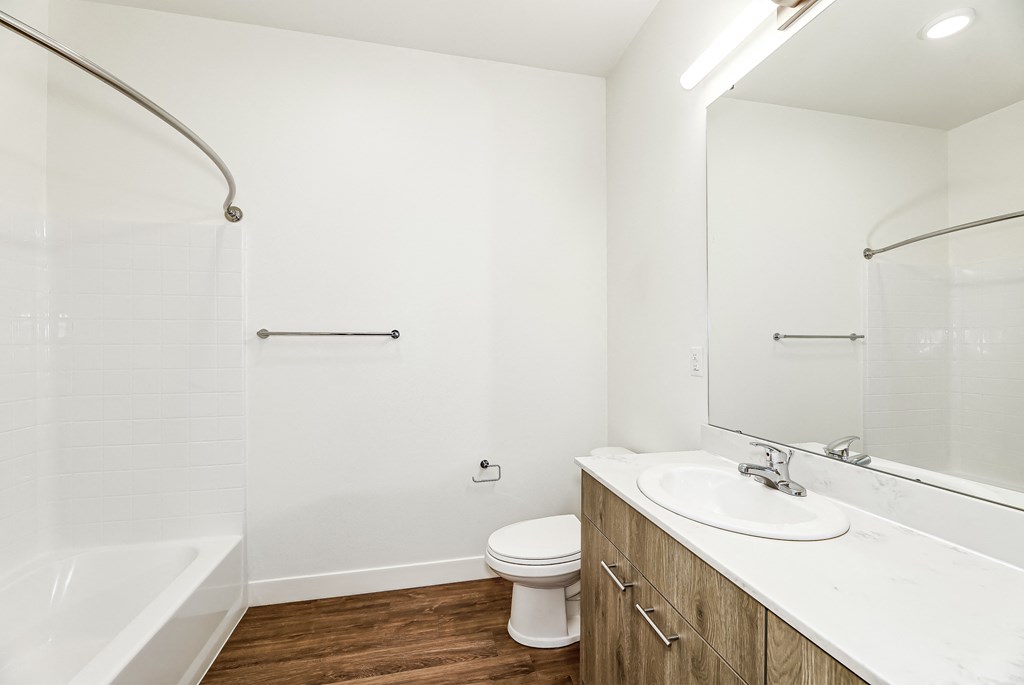 a bathroom with white walls and wood flooring