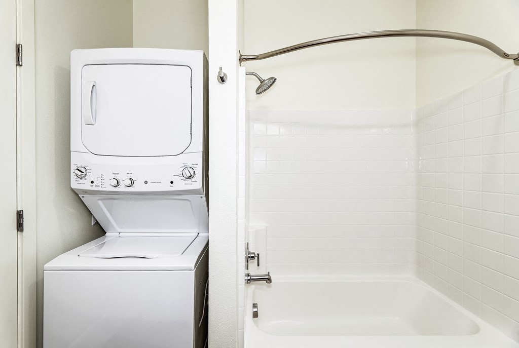 a bathroom with a washer and dryer and a bathtub