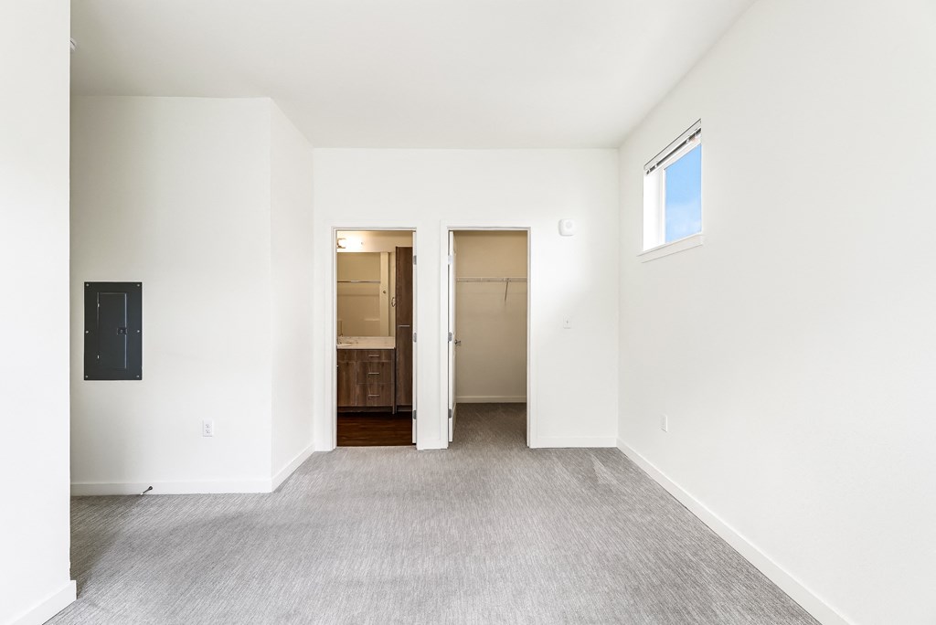 an empty living room with white walls and a door to a bathroom