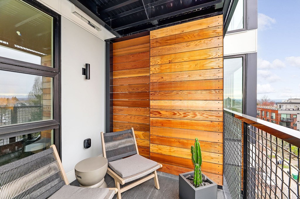 a balcony with two chairs and a wooden privacy wall