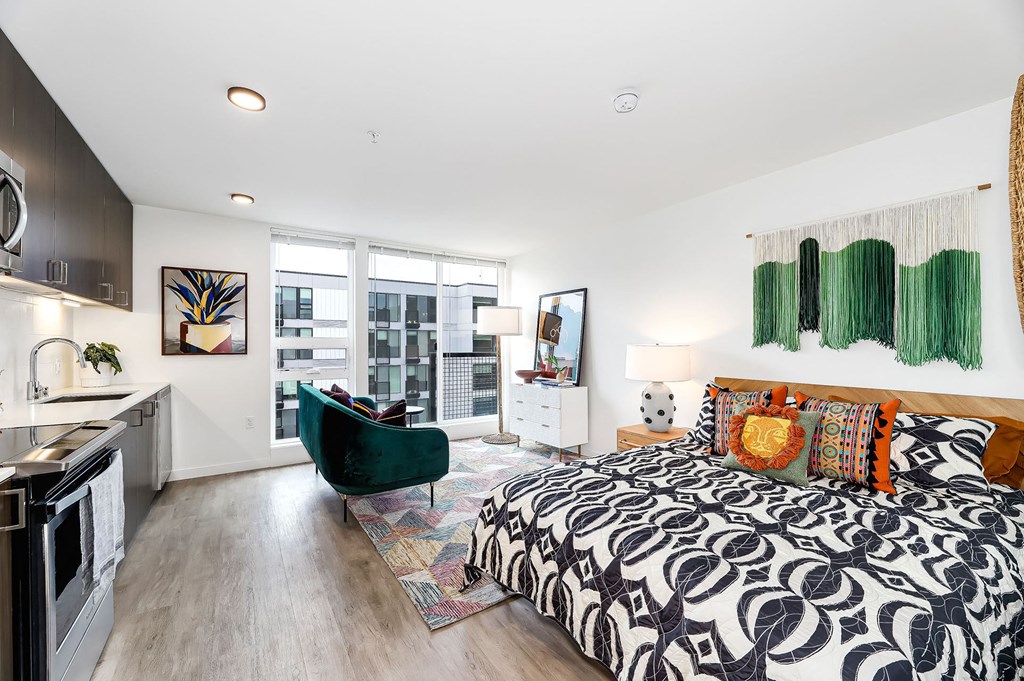 a bedroom with a bed and a kitchen and a window