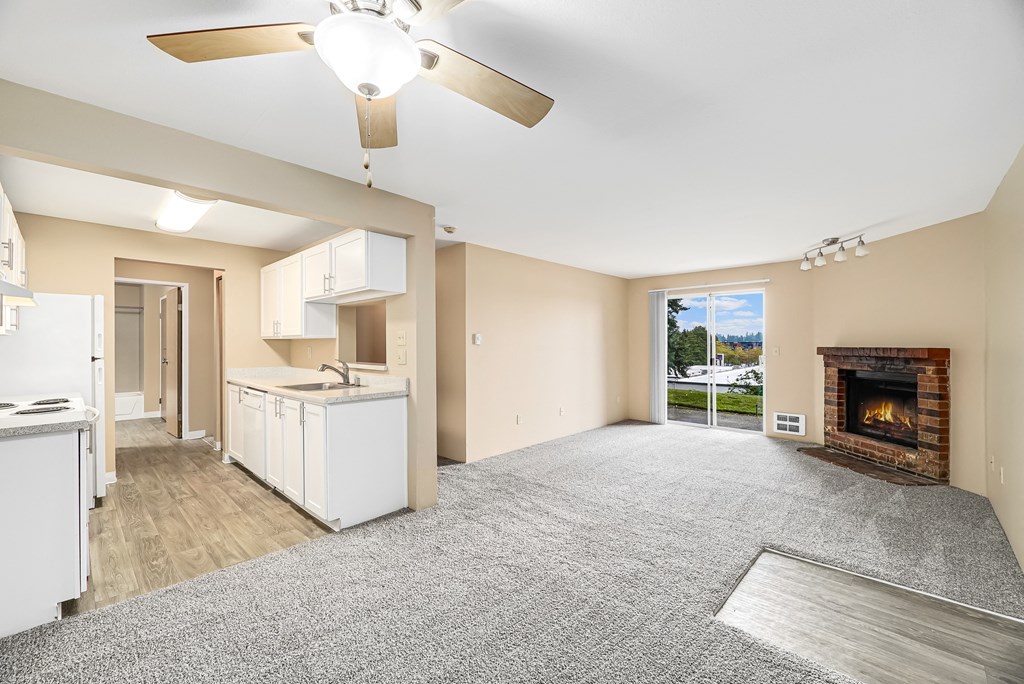 an empty living room with a fireplace and a kitchen