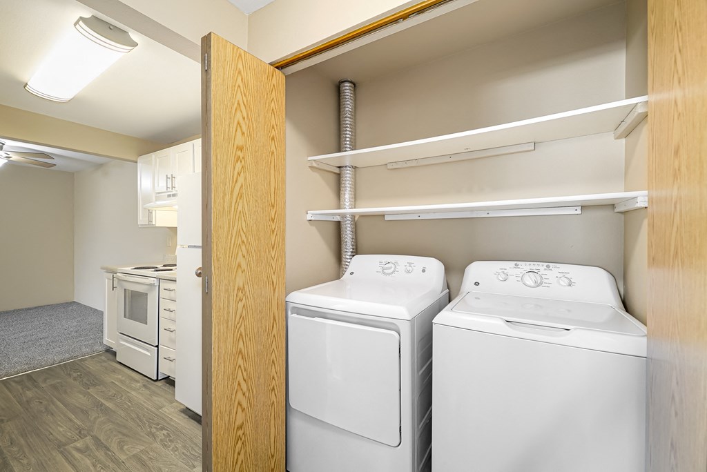 a white washer and dryer in a room with a door to a closet