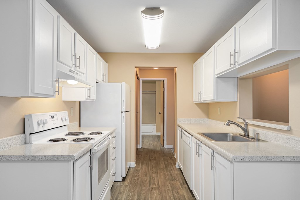 a kitchen with white cabinets and white appliances and a sink