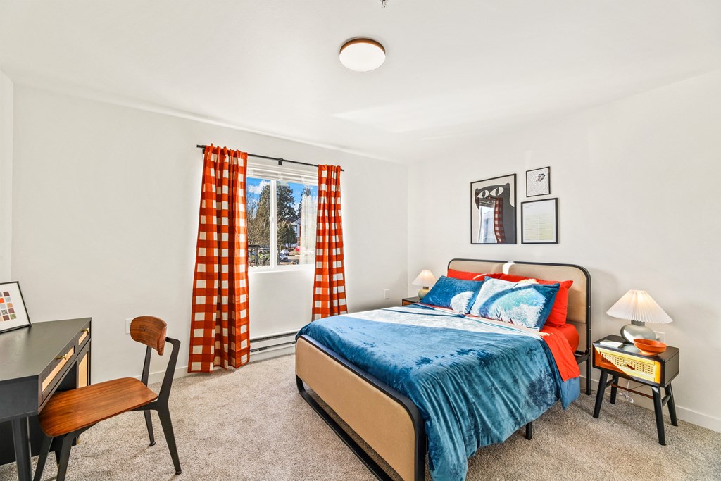 a bedroom with a bed and a desk and a window