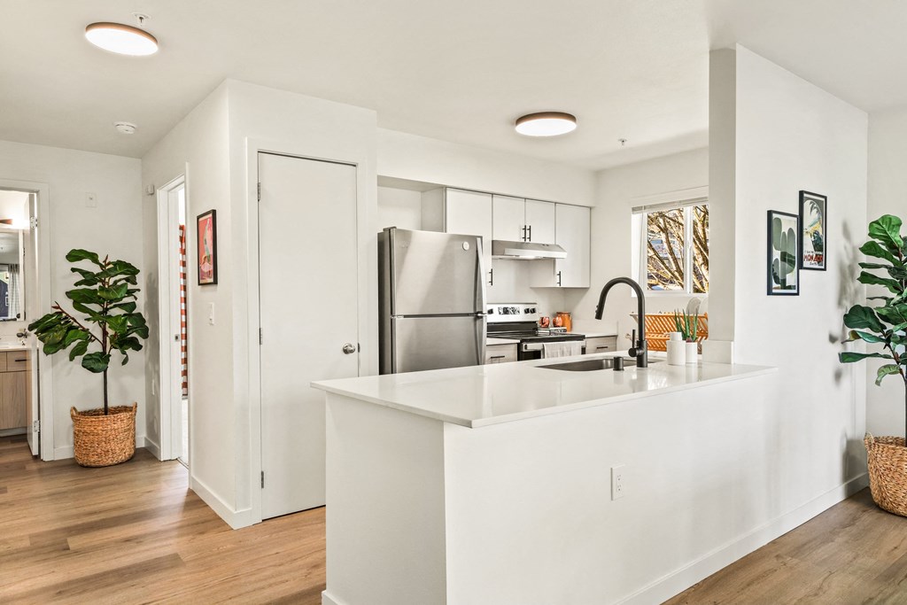 a kitchen with a white counter top and a stainless steel refrigerator