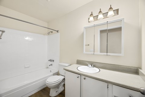 A white bathroom with a toilet, sink, and bathtub.