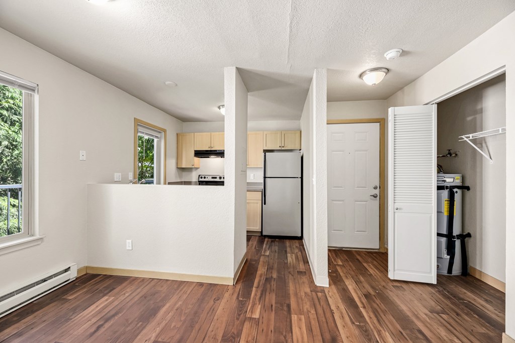 A kitchen with a white fridge and wooden floors.
