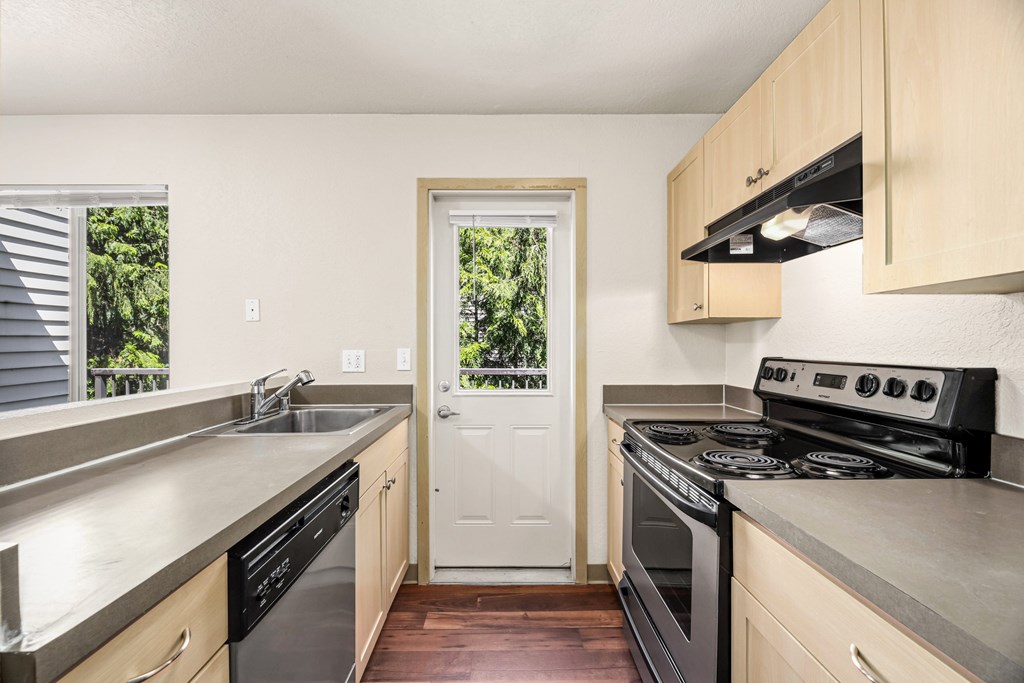 A kitchen with a stove, sink, and cabinets.