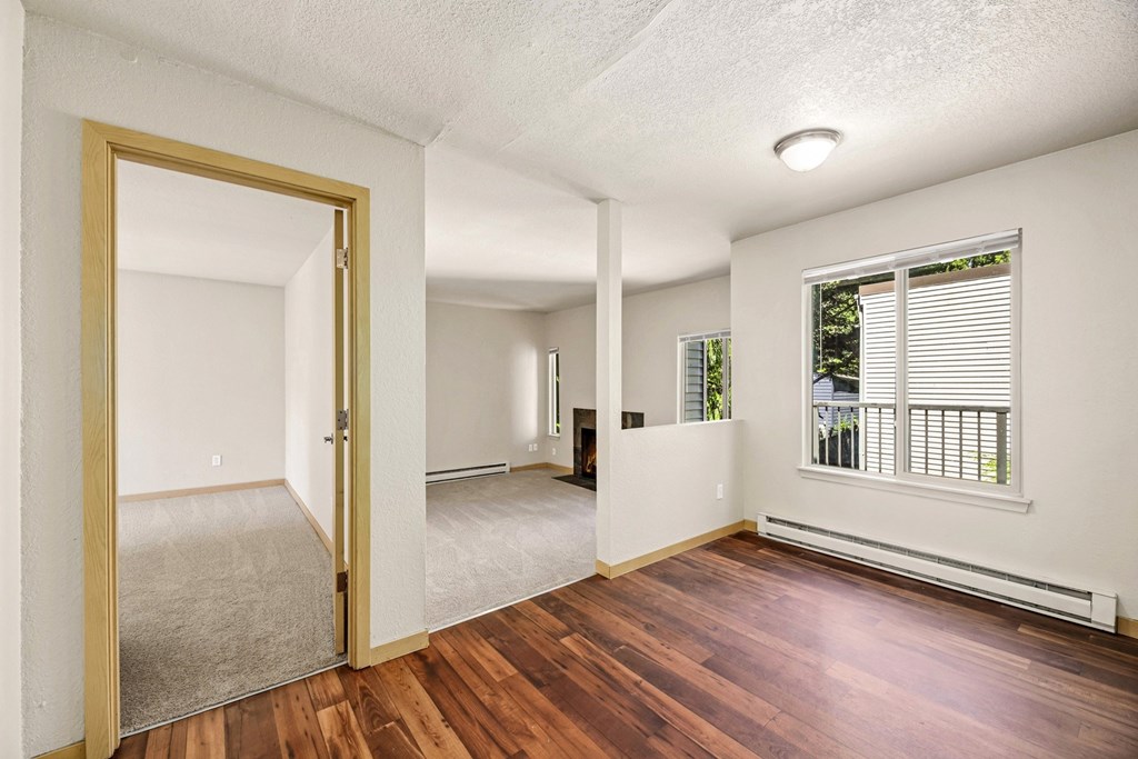 A room with a wooden floor and a large mirror on the wall.