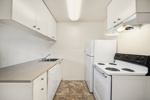 A small kitchen with a white stove and white cabinets.