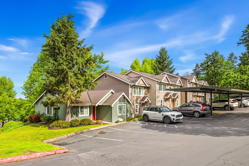 A parking lot in front of a building with cars parked.