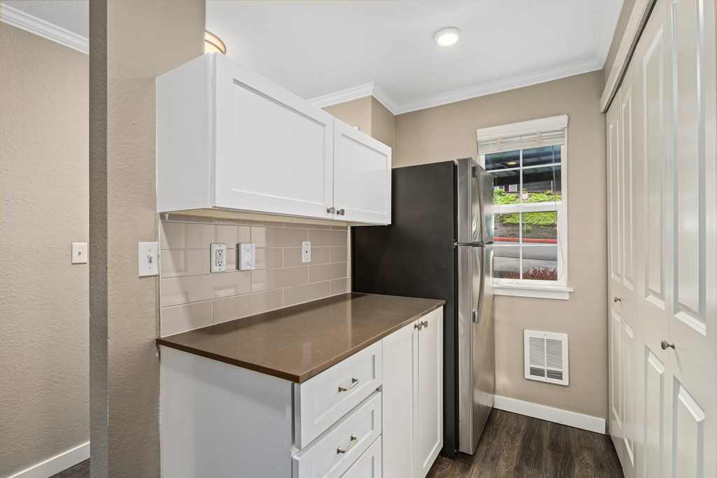 A kitchen with white cabinets and a black refrigerator.