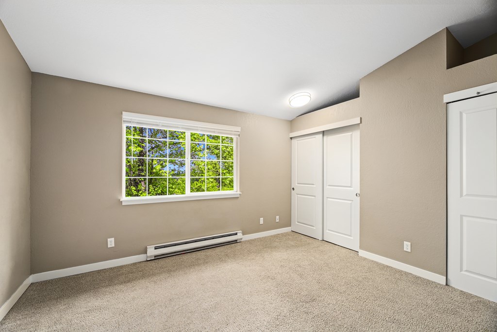 A room with a window and a carpeted floor.