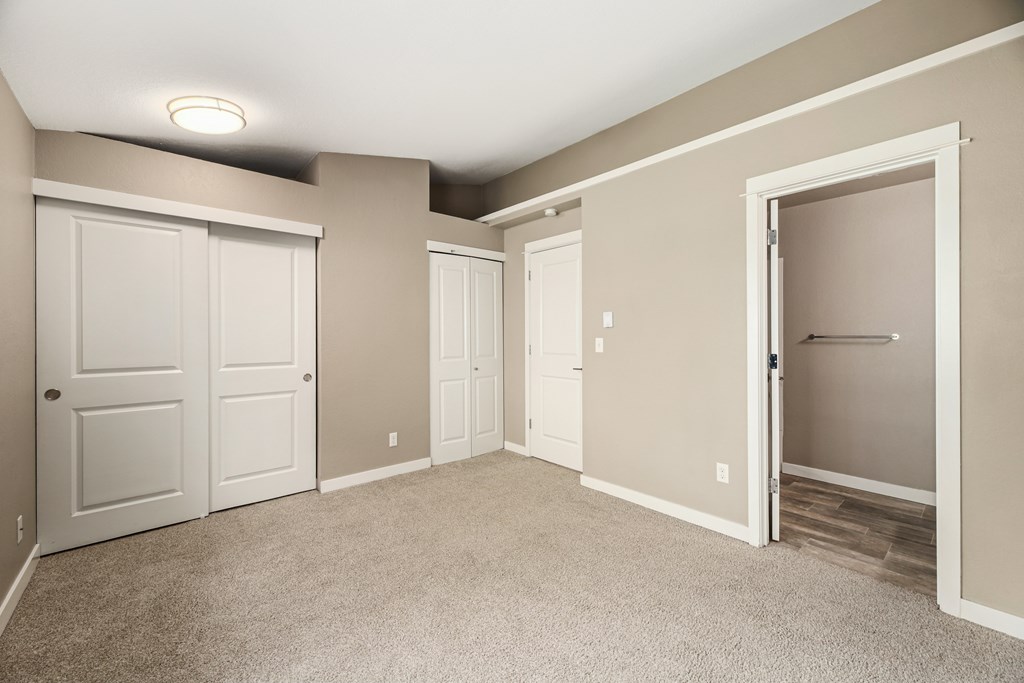 A room with white doors and carpeted floor.