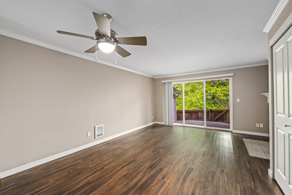 A room with a ceiling fan and wooden flooring.
