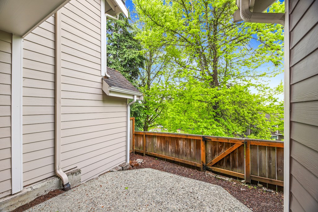 A small backyard with a wooden fence and a gravel path.