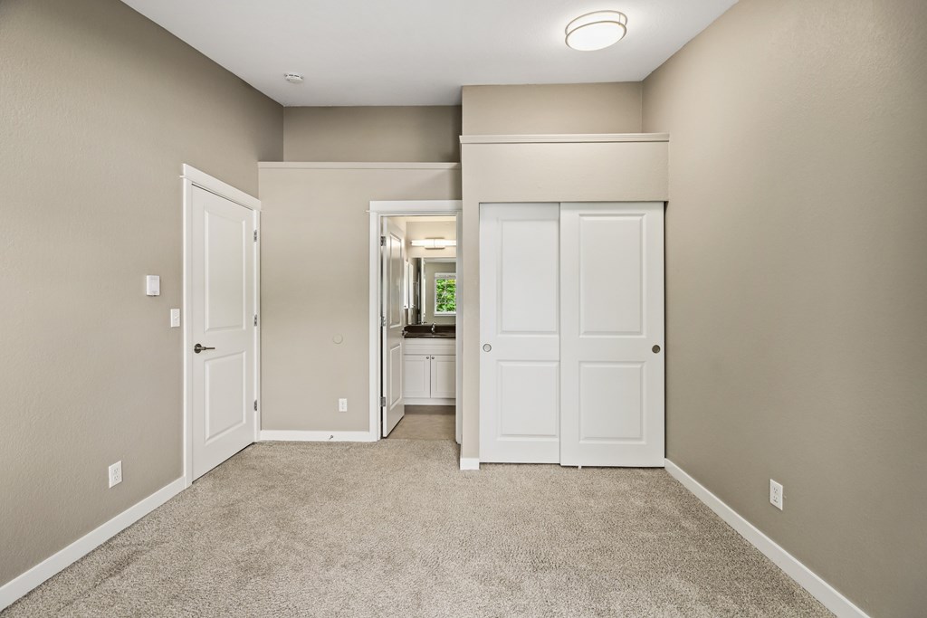 A room with a carpeted floor and two white doors.