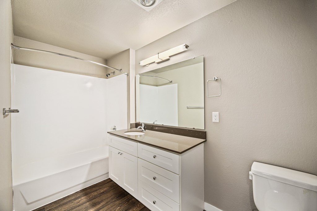A white bathroom with a sink, mirror, and toilet.