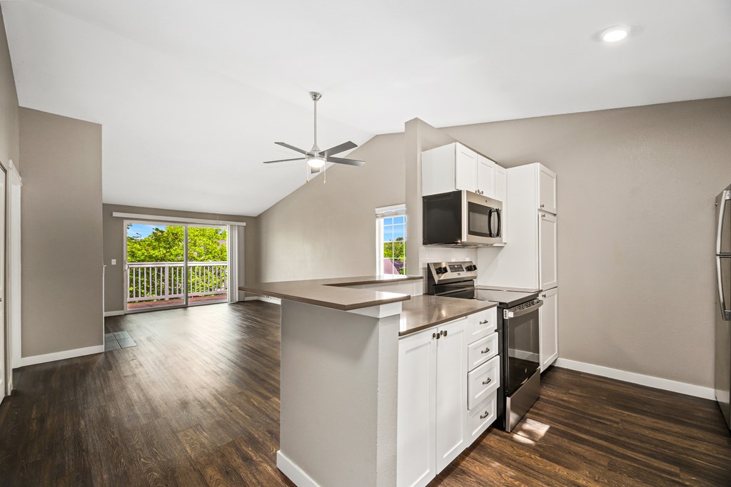 A modern kitchen with white cabinets and a wooden floor.
